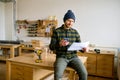 Man carpenter sitting on table at modern joinery workshop