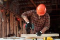 A man carpenter twists a screw into a tree with an electric screwdriver, male hands with a screwdriver close-up. Work with wood Royalty Free Stock Photo