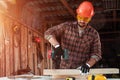 A man carpenter twists a screw into a tree with an electric screwdriver, male hands with a screwdriver close-up. Work with wood Royalty Free Stock Photo