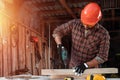 A man carpenter twists a screw into a tree with an electric screwdriver, male hands with a screwdriver close-up. Work with wood Royalty Free Stock Photo