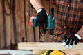 A man carpenter twists a screw into a tree with an electric screwdriver, male hands with a screwdriver close-up. Work with wood Royalty Free Stock Photo