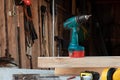 A man carpenter twists a screw into a tree with an electric screwdriver, male hands with a screwdriver close-up. Work with wood Royalty Free Stock Photo