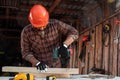 A man carpenter twists a screw into a tree with an electric screwdriver, male hands with a screwdriver close-up. Work with wood Royalty Free Stock Photo