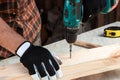 A man carpenter twists a screw into a tree with an electric screwdriver, male hands with a screwdriver close-up. Work with wood Royalty Free Stock Photo