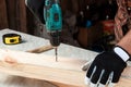 A man carpenter twists a screw into a tree with an electric screwdriver, male hands with a screwdriver close-up. Work with wood Royalty Free Stock Photo