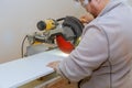 Man carpenter using circular electro saw cutting laminated white shelves