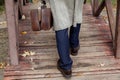 Man with carpetbag and coat walks on wooden bridge