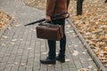 Man with carpetbag in jacket stands in alley of autumn park Royalty Free Stock Photo