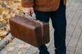 Man with carpetbag in jacket stands in alley of autumn park Royalty Free Stock Photo