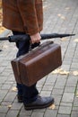 Man with carpetbag in jacket stands in alley of autumn park Royalty Free Stock Photo