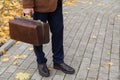 Man with carpetbag in jacket stands in alley of autumn park Royalty Free Stock Photo