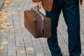 Man with carpetbag in jacket stands in alley of autumn park Royalty Free Stock Photo