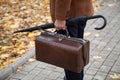 Man with carpetbag in jacket stands in alley of autumn park Royalty Free Stock Photo