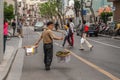 Man carries baskets with shoulder pole on street, Shanghai, China