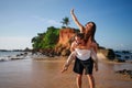 Joyful couple enjoys a romantic piggyback ride on a serene beach. Man carries girlfriend, playful adventure by sea