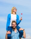 Man carries girlfriend on shoulders, sky background. Couple happy date having fun together. Woman holds heart on stick