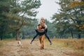 Man carries his wife and daughter on his back at forest path next to dog during walk Royalty Free Stock Photo