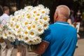 A man carries a huge bouquet of white daisies for congratulations for a wedding, birthday