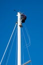 A man carries out work on the top of the mast of a sailboat