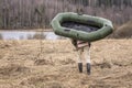 Man carries a rubber inflatable boat on the shore of the lake Royalty Free Stock Photo