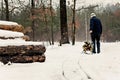 Man carries wood on a sled in the winter snowy forest