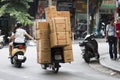Man carrying boxes for delivery on a motorbike in a street of Hanoi.