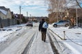 Man carrying purchases from a remote local shop walking on a snowy, slippery street