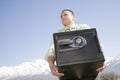 Man carrying safe near mountains Royalty Free Stock Photo