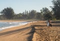 Man carrying surfboard to ocean on sandy Hanalei beach