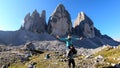 Man carrying woman piggyback with the close up view on the Tre Cime di Lavaredo (Drei Zinnen) in Italian Dolomites. Royalty Free Stock Photo