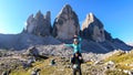 Man carrying woman piggyback with the close up view on the Tre Cime di Lavaredo (Drei Zinnen) in Italian Dolomites. Royalty Free Stock Photo