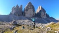 Man carrying woman piggyback with the close up view on the Tre Cime di Lavaredo (Drei Zinnen) in Italian Dolomites. Royalty Free Stock Photo