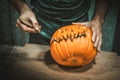 man carves a halloween pumpkin with a knife background Royalty Free Stock Photo