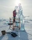 A man carves a sculpture out of ice. A sculptor carves an ice sculpture using a chainsaw. New Year's Eve celebrations. Royalty Free Stock Photo