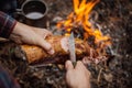 Man carving grilled rabbit meat in forest camp. Top view.