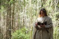 A man in a cassock spends a ritual in a dark forest