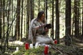 A man in a cassock spends a ritual in a dark forest