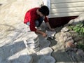 Man in casual clothes does work on laying paving slabs, top view. Young adult dark-haired worker knocks a rubber mallet on a tile