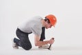 Man in casual clothes and orange colored hard hat have some work using hammer. White background Royalty Free Stock Photo