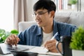 the man in casual clothes working with a laptop, computer, smart phone, calculator sitting on the sofa in the living room at home Royalty Free Stock Photo