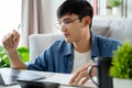 the man in casual clothes working with a laptop, computer, smart phone, calculator sitting on the sofa in the living room at home Royalty Free Stock Photo