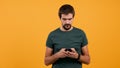 Man in casual t-shirt typing and browing on his smartphone