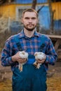 A man caucasian farmer satisfied portrait in a shirt and overalls, holds a two dwarf white chickens close up in his hands poultry Royalty Free Stock Photo