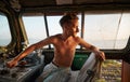 Man Caucasian seated in the driver& x27;s cab of a large locomotive looking back