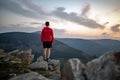 Man celebrating sunset looking at view in mountains