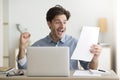 Man Celebrating Victory Sitting At Laptop Holding Letter At Workplace