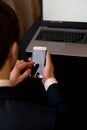 Man with cellphone sitting at a table working on his laptop computer Royalty Free Stock Photo