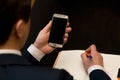 Man with cellphone sitting at a table working on his notebook Royalty Free Stock Photo