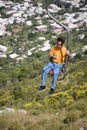 Man on chair lift looking at cell phone messages overlooking Capri, an Italian island off the Sorrentine Peninsula on the south si