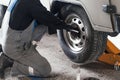 Man changes wheel of car in car service. Professional auto mechanic in overalls removes wheel from truck in garage Royalty Free Stock Photo